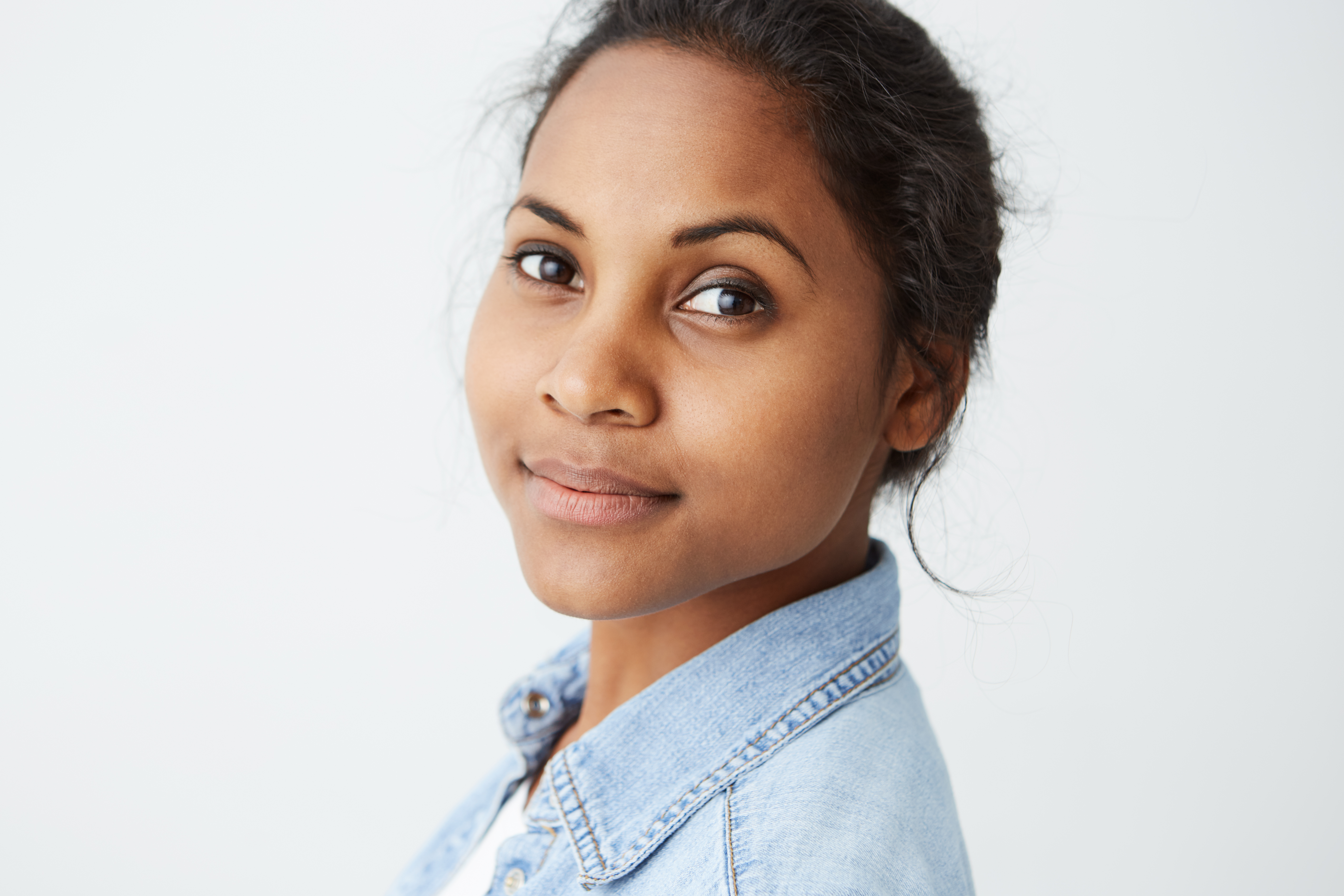 Highly-detailed close up portrait of beautiful African-american woman with perfect clean skin and black eyes looking at the camera with calm face expression on white background.